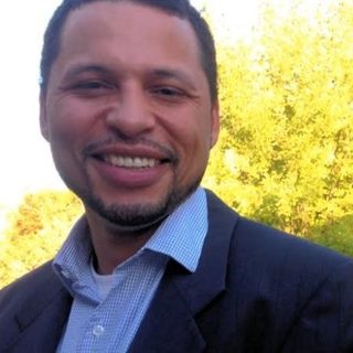 Alex Hartman, founder of HustleForge LLC, smiling outdoors in a dark blazer